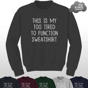 Op de afbeelding: Een donkergrijs sweatshirt met de tekst "This is my too tired to function sweatshirt" in wit.