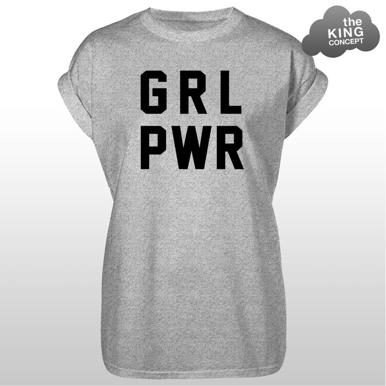 Pode incluir: Uma camiseta cinza mesclada com mangas enroladas. A camiseta apresenta o texto preto "GRL PWR" em uma fonte em negrito e em blocos. Um gr&aacute;fico em forma de nuvem cinza com o texto "the KING CONCEPT" est&aacute; no canto superior direito.