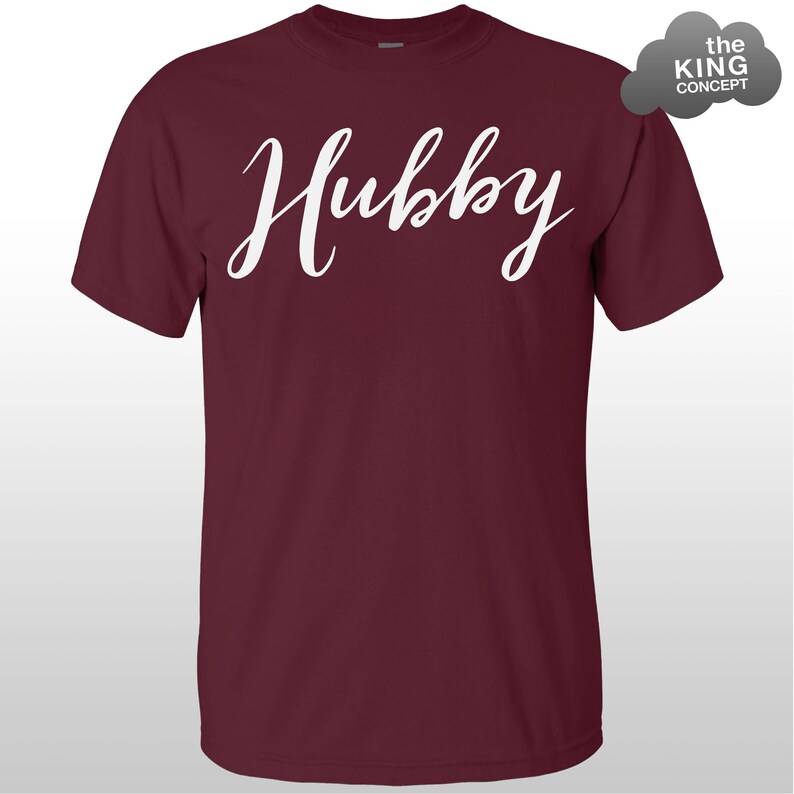 Może przedstawiać: Bordowy t-shirt z napisem "Hubby" napisanym białym, ozdobnym pismem.