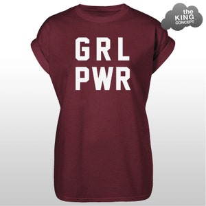 Pode incluir: Camiseta bord&ocirc; com mangas enroladas. O texto branco "GRL PWR" &eacute; impresso em negrito na frente. Um logotipo cinza em forma de nuvem com o texto "the KING CONCEPT" est&aacute; no canto superior direito.