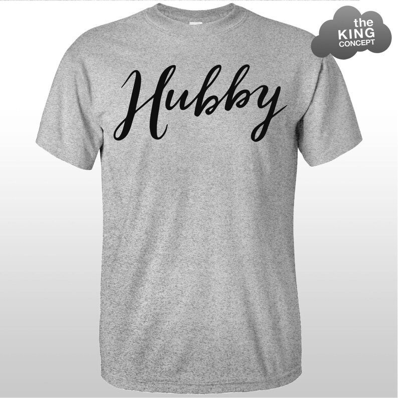 Może przedstawiać: Szary T-shirt z napisem "Hubby" napisanym czarnym, ozdobnym pismem.