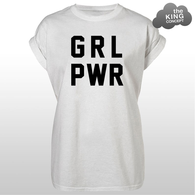 Pode incluir: Uma camiseta branca com mangas enroladas. O texto preto "GRL PWR" &eacute; impresso em negrito na frente. Uma nuvem cinza com "the KING CONCEPT" est&aacute; no canto superior direito.
