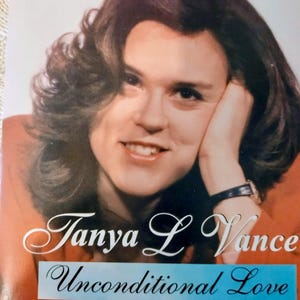 May include: A vintage photograph featuring a woman with dark, wavy hair, resting her head on her hand. The image includes the text "Tanya L Vance" above the words "Unconditional Love" on a blue banner.