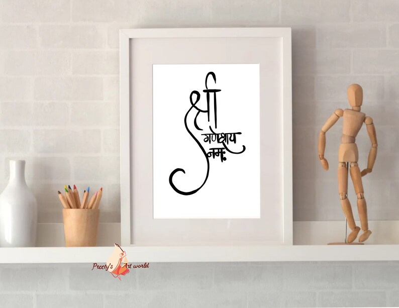 May include: A white framed print with black calligraphy that reads "Shree Ganeshay Namah". The print is on a white shelf with a wooden figurine and a vase of pencils.
