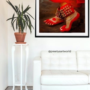 May include: A painting of a pair of feet wearing red anklets with gold bells. The feet are painted in a red color with a red dot on the big toe of each foot. The background is a dark brown color.