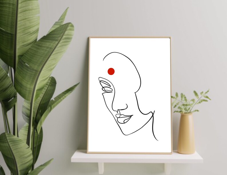 May include: A black and white line drawing of a woman's face with a red dot on her forehead. The drawing is in a simple, minimalist style.