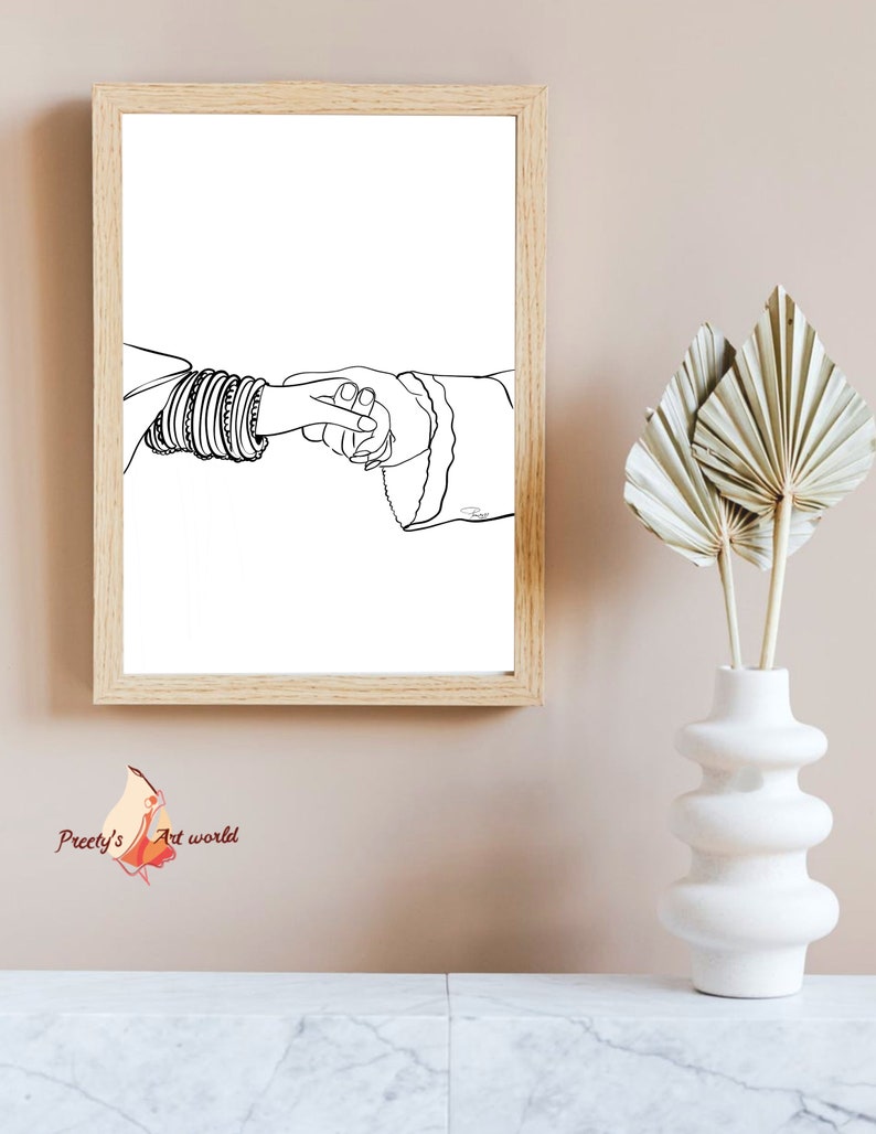 May include: A black and white line drawing of two hands holding each other. The hand on the left is wearing several bangles. The drawing is framed in a light wood frame.