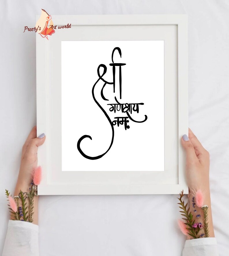 May include: A white framed print with black calligraphy that reads "Shree Ganeshay Namah".