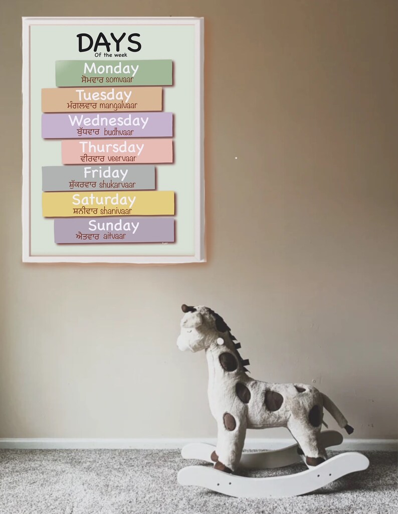 Puede incluir: Un gr&aacute;fico colorido con los d&iacute;as de la semana en ingl&eacute;s y punjabi. El gr&aacute;fico est&aacute; enmarcado y colgado en una pared. Un caballo de balanc&iacute;n de peluche con forma de jirafa est&aacute; en primer plano.