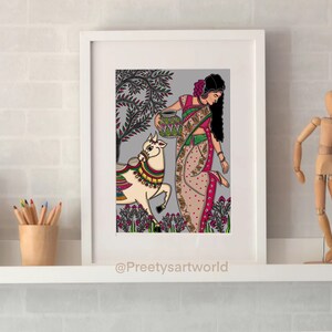 May include: A framed illustration of a woman in a colorful sari carrying a pot on her head, walking with a white cow in a field. The background is a gray and green landscape with flowers. The artwork is signed "@Preethysartworld".