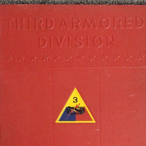 May include: Red book cover with the title "Third Armored Division" in gold lettering. The book also has a gold star pattern and a yellow triangle with a black tank and the number "3" in white. The text "Combat Command B 1950" is in gold lettering at the bottom.