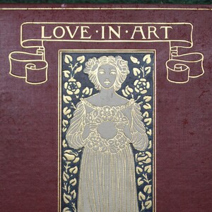 May include: A maroon book titled "LOVE IN ART" with gold lettering and accents. The cover features a gold illustration of a woman in a flowing gown holding a wreath, surrounded by floral designs. The author's name, MARY KNIGHT POTTER, is at the bottom.