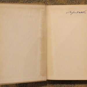 Op de afbeelding: Een open boek met een blanco pagina aan de linkerkant en een pagina met een blauwe inktsignatuur aan de rechterkant.