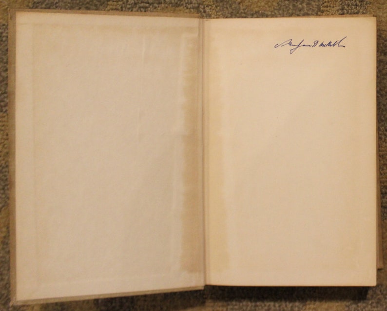 Op de afbeelding: Een open boek met een blanco pagina aan de linkerkant en een pagina met een blauwe inktsignatuur aan de rechterkant.