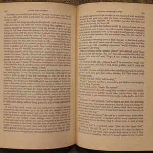 Op de afbeelding: Een open boek met een cr&egrave;mekleurige kaft en zwarte tekst. Het boek is open op pagina 313 en 314. De tekst op de pagina's gaat over een gesprek tussen twee mensen. De tekst op de linkerpagina gaat over een man die kalm en rustig is, terwijl de tekst op de rechterpagina over een vrouw gaat die emotioneler is.