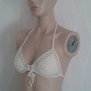 May include: A white crocheted bikini top with a delicate floral design at the center.
