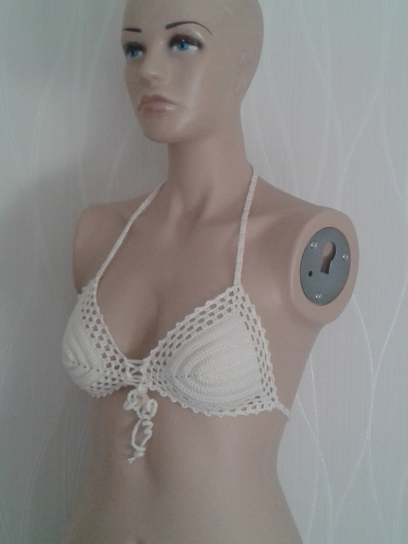 May include: A white crocheted bikini top with a delicate floral design at the center.