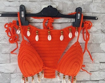 May include: Orange crochet bikini top with white shell accents and brown beads.