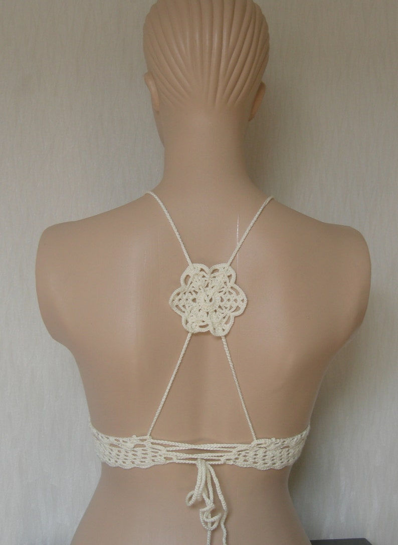 May include: White crochet halter top with a floral design on the back. The top has adjustable straps and ties at the back.