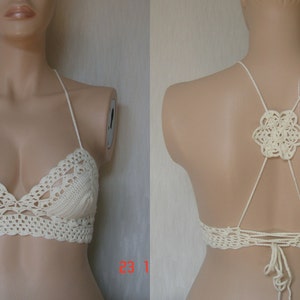 May include: A white crocheted halter top with a floral design on the back. The top is made with a delicate crochet stitch and has a relaxed fit.