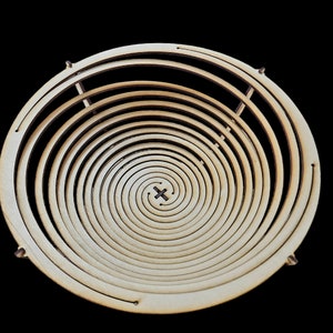 Può includere: Una ciotola di legno con un design a spirale. La ciotola è realizzata in legno chiaro e ha una finitura naturale.