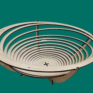 Puede incluir: Un cuenco de madera con un diseño circular. El cuenco está hecho de múltiples capas de madera, creando un patrón de círculos concéntricos. El cuenco es de color marrón claro.