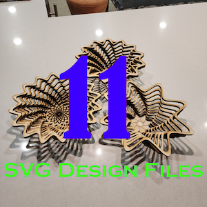 May include: Two wooden bowls with a spiral design. The bowls are made of thin strips of wood that are layered and interlocked to create a three-dimensional effect. The bowls are stacked on top of each other, and the number "11" is superimposed over the bowls in a blue font. The text "SVG DESIGN FILES" is written in green at the bottom of the image.