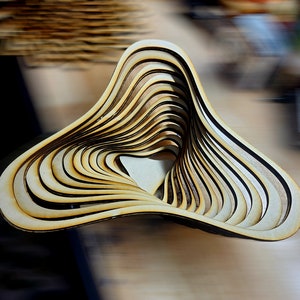 Può includere: Una ciotola di legno con un design unico e stratificato. La ciotola è realizzata con sottili strisce di legno impilate e curve per creare una forma a spirale organica.