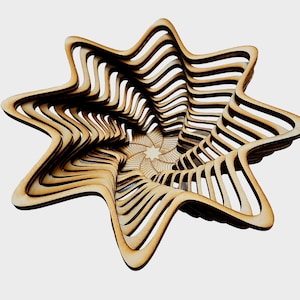 Puede incluir: Un cuenco de madera en forma de estrella con un diseño en espiral superpuesto. El cuenco está hecho de madera marrón claro y tiene un acabado natural.