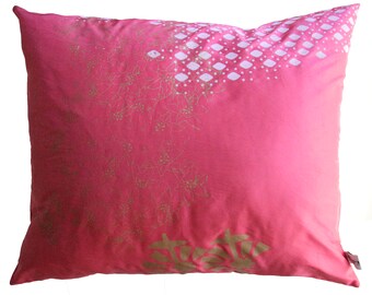 Pode incluir: Uma almofada rosa com um padrão floral branco e dourado. A almofada é feita de um tecido macio e confortável e tem um efeito degradê sutil.