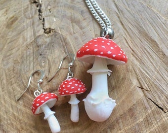 Op de afbeelding: Een set rode en witte paddenstoel oorbellen en een ketting. De paddenstoel bedels zijn gemaakt van polymer clay en hebben witte stippen op de rode hoeden. De ketting heeft een zilveren ketting.