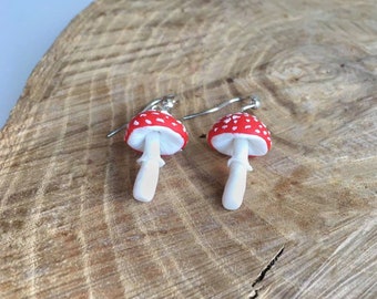 Op de afbeelding: Een paar rode en witte paddenstoel oorbellen met zilveren haakjes. De paddenstoelen hebben witte stippen op de rode hoeden en witte stelen.