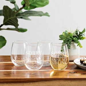 May include: Set of four clear glass wine glasses with the text "Sorry you had to raise my sibling, your favorite" etched on the front of each glass.