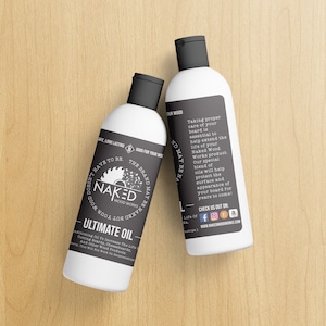 May include: Two white bottles of wood oil with black labels. The labels have a saw blade logo and the text "Naked Wood Works" and "Ultimate Oil". The text on the right bottle reads "Taking proper care of your board is essential to help extend the life of your Naked Wood Works product. Our special blend of oils will help protect the surface and appearance of your board for years to come!"