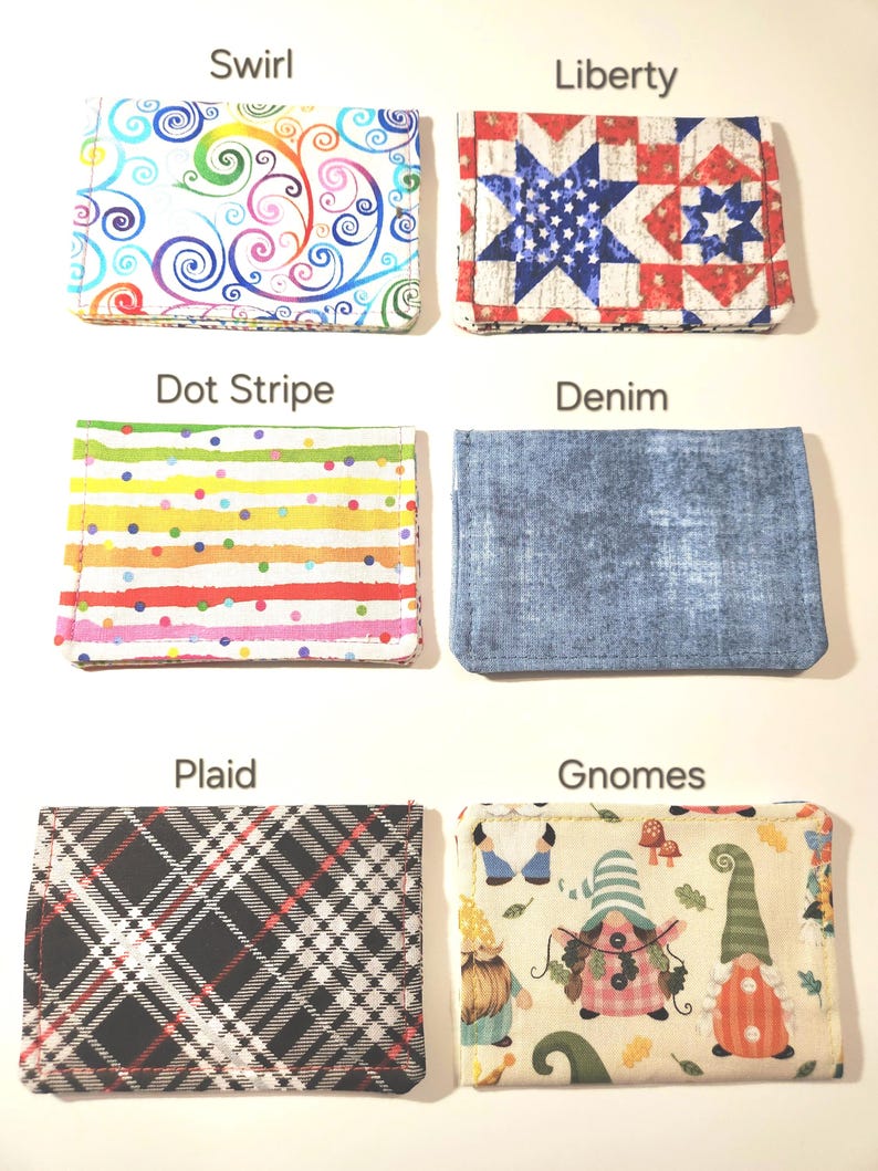 May include: Six rectangular fabric card holders arranged in two columns. Patterns include a colorful swirl, a red, white, and blue star quilt design labeled Liberty, a multi-colored dot stripe, a blue denim texture, a black and white plaid, and a gnome print.
