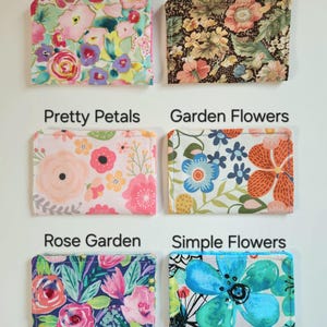 May include: Six rectangular fabric pouches with floral patterns labeled Summer Blooms, Wildflower, Pretty Petals, Garden Flowers, Rose Garden, and Simple Flowers. Each pouch features distinct colorful botanical prints on a white or dark background.