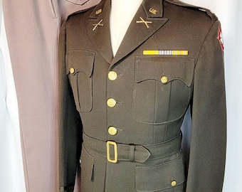 May include: A dark green military uniform with gold buttons and a brown belt. The uniform has a pocket on the left chest with a yellow and white ribbon. The uniform has the text "U.S." on the collar and "SUPERIOR MODEL FORM CO" on the right side of the chest.