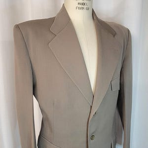 May include: A beige blazer with a single button closure and two flap pockets on the front. The blazer is on a mannequin with the label "Superior Model Form Co."