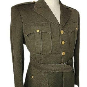May include: A dark green military-style jacket with a high collar, four pockets, and a belt. The jacket has gold buttons and is made of a thick, textured fabric.