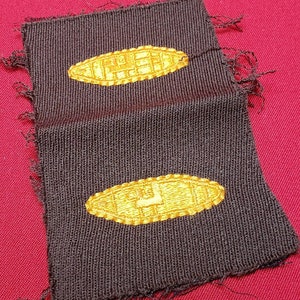 Peut inclure: Deux patchs en tissu brun avec des formes ovales brodées en jaune. Les ovales ont un motif tissé.