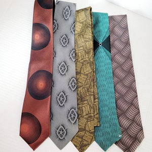 May include: Five patterned neckties in various colors and designs. The ties are arranged in a row, with the brown tie on the left and the gray tie on the right.