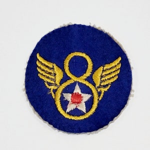 May include: A blue felt patch with a gold embroidered number 8 surrounded by wings and a star. The star has a red center and white points.