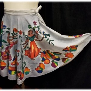 May include: A white wrap skirt with a colorful print of people, flowers, and pottery. The skirt has a tie closure at the waist.