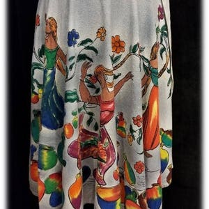 May include: A light blue wrap skirt with a colorful print of dancing figures and fruit. The skirt has a tie closure at the side.