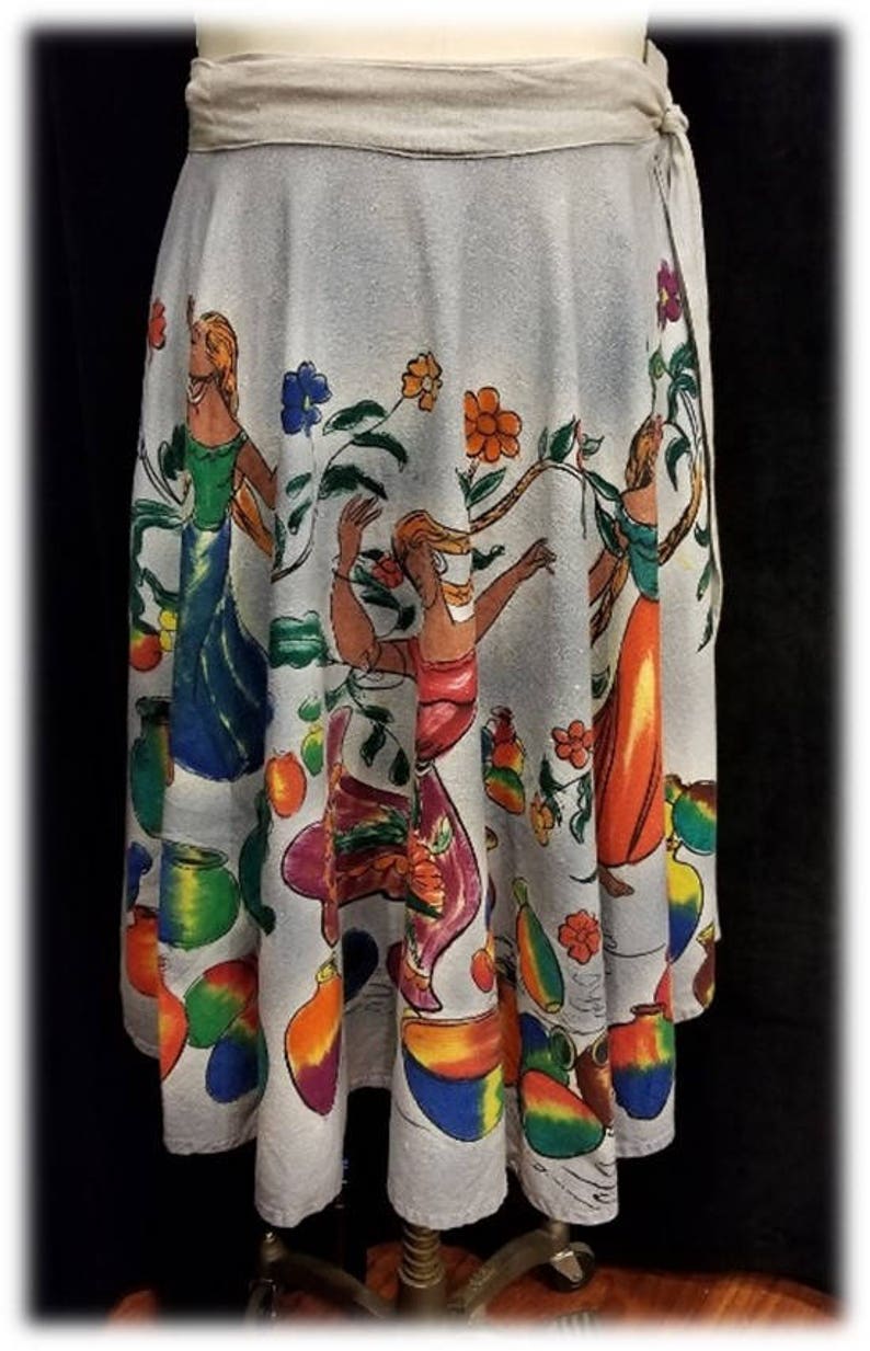 May include: A light blue wrap skirt with a colorful print of dancing figures and fruit. The skirt has a tie closure at the side.