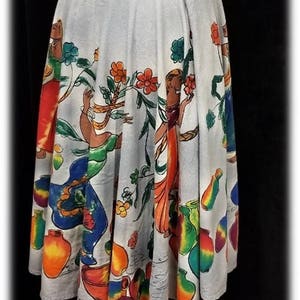 May include: A white cotton skirt with a colorful print of women and flowers. The skirt has a wide waistband and a full, flowing silhouette.
