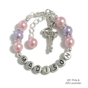 May include: A silver charm bracelet with a ballerina charm, pink and lavender beads, and the name "MADISON" spelled out in silver beads.