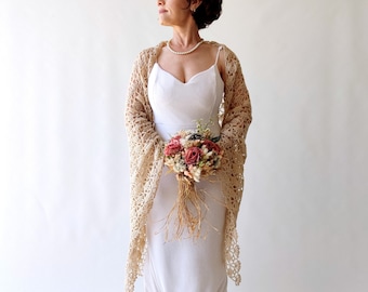 May include: A bride wearing a white dress with a crocheted shawl and holding a bouquet of dried flowers.