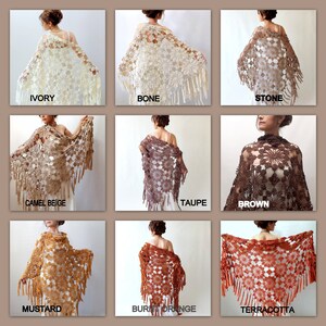 May include: A collection of crochet shawls in various colors, including ivory, bone, stone, camel beige, taupe, brown, mustard, burnt orange, and terracotta. The shawls feature a delicate floral pattern and fringe trim.