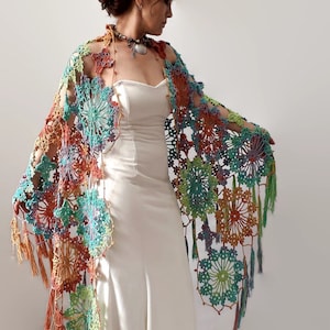 May include: A colorful crochet shawl with a floral pattern and fringe. The shawl is made with a variety of colors, including orange, green, blue, and purple.
